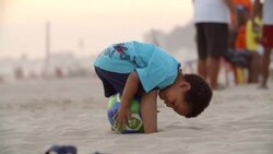 Little boy pats and poses with Brazilian soccer ball on Copacabana Beach Stock Footage