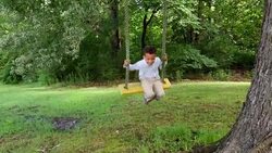 MS Smiling young boy on tree swing in backyard of home Stock Footage