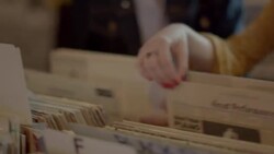 Young woman looks through vinyl albums with friends and nods to music in record store Stock Footage