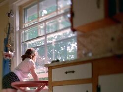 Selective rack focus wide shot redheaded girl looking out window then turning to camera to smile / Nova Scotia Stock Footage
