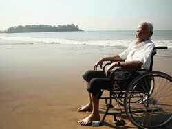 Senior man sitting on the wheelchair on the beach Stock Footage