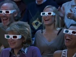 Medium shot zoom out audience wearing 3-D glasses reacting to movie out of frame with shock and pleasure Stock Footage