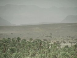 Landscape shot of vast dusty and dark terrain, overlooked by misty mountains. Stock Footage