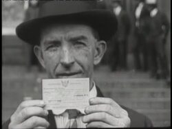 A man in a hat holds up a draft card. News Clip