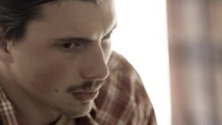 Young man sulks on motel bed as young woman paces back and forth behind him Stock Footage