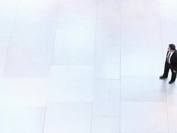  HA Businessman standing on large empty tiled floor hanging up cell phone and walking away / Seattle, Washington, United States Stock Footage