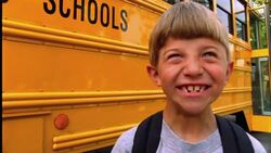 A young boy laughs in front of his school bus. Stock Footage