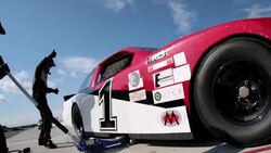 Pit-crew lowers jack, race-car driver speeds off, pit-crew celebrates Stock Footage