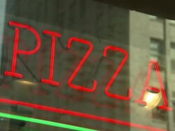A pizza sign lights the window of a restaurant. Stock Footage