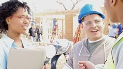 Construction managers talk with charity staff member about progress of charity home Stock Footage