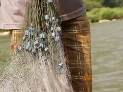CU TD SLO MO Shot of man tying fishing nets together / Ou river, Luang Prabang, Laos Stock Footage