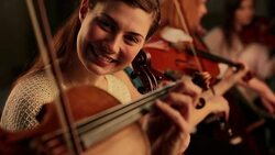 Violinist in orchestra smiles and lifts violin Stock Footage