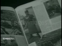 1938: SUDETENLAND: DRAMATIZATION: Family in home w/ young adult males holding newspapers. CU Female hands turning page of magazine w/ articles & photographs of German Nazi soldiers, troops. Young adult male holding magazine. Instructional Video