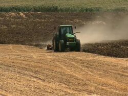 MS Shot of barren farm landscape with green tractor plowing field / Judea, Israel Stock Footage