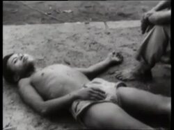 B/W 1960's wounded Asian man lying on ground / Saigon / NO SOUND Stock Footage