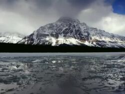 Time lapse panning frozen body of water with snow-covered mountain along banks Stock Footage