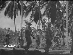 1942: PACIFIC FRONT: HA XWS US Soldiers walking narrow path in open field. VS US Marines walking, by palm trees, over bridge w/ palm trees BG. WS US Marines coming ashore in landing craft w/ sailor seated on bow. Pacific Theater, Campaign, WWII. Instructional Video