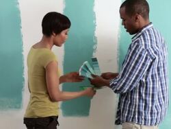Couple comparing color swatches with paint on wall Stock Footage