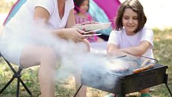 Young Mother And Daughter Grilling Meat On Barbecue Stock Footage