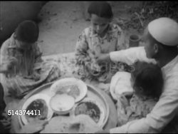 1952: EGYPTIAN AGRICULTURE: WS Mohamed Amer family gathered inside for noon main meal, VS Eating, dipping in bowls w/ flatbread, wife Sadia eating, children & Mohamed eating. Instructional Video