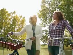 Smiling women standing with bicycles in park Stock Footage