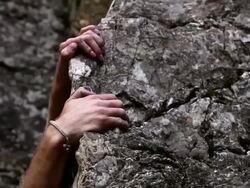 Closeup tracking shot of a man's hands trying to find a solid grip while rock-climbing. Stock Footage