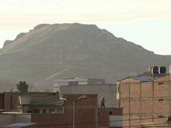 Man on roof with pole in sunlight with mountain in b/g, Cochabamba, Bolivia Stock Footage