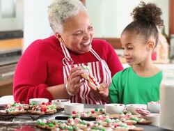 MS Grandmother and Granddaughter Decorating Gingerbread Men Cookies in Kitchen / Richmond, Virginia, USA Stock Footage