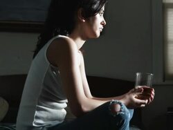 woman sitting on a hotel bed rocking back and forth and talking to herself Stock Footage