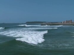 PAN Ocean beach waves heading toward sandy shoreline in front of hi-rise buildings / Durban, Kwa ulu Natal, South Africa Stock Footage