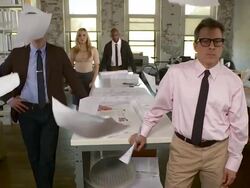 Full shot. Boss in foreground as employees stand in background. They all look in the camera as paper is strewn about in slow motion. Stock Footage