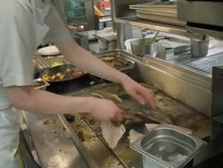 POV cook working on hot plate cooking fish in a restaurant kitchen Stock Footage