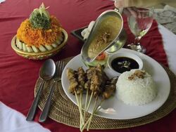 MS Being serve peanut souce over chicken sate with fried chicken skewer with steamed rice, Kerupuk crackers and balinese food dish at Asia / Ubud, Bali, Indonesia Stock Footage