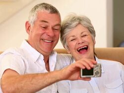 Senior couple sitting on couch taking a selfie Stock Footage