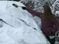 CU Girl removing heavy snow layers from car / Saarburg, Rhineland-Palatinate, Germany Stock Footage