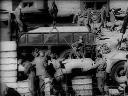B/W 1961 high angle soldiers guiding cement slab being lowered by crane / Berlin Wall construction Stock Footage
