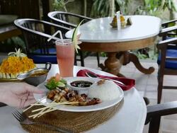 MS Being serve dish of chicken Sate, fried Chicken skewer with steamed rice, kerupuk crackers, watermelon juice and balinese food at Asia / Ubud, Bali, Indonesia Stock Footage