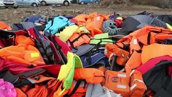 Life jackets and remains of boats left by Syrian migrants fleeing the war and escaping to Europe, landing on the Greek island of Lesvos on the north coast at Efthalou. Up to 4,000 migrants a day are landing on the island and overwhelming the authorities. T Stock Footage