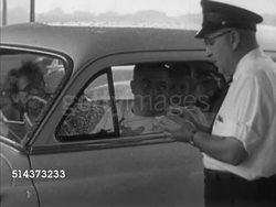 1952: CANADA: BORDER CROSSING: WS Cars trying to merge in rain, border booths & cars BG. MS Agent standing next to car taking notes, SOT asking driver if coming back this way, anything in car other than clothes, taking identification, handing back. Instructional Video