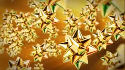 Shiny gold gift bows float against a golden background. Stock Footage