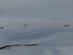 Aerial of two helicopters flying in mountains in winter. Stock Footage