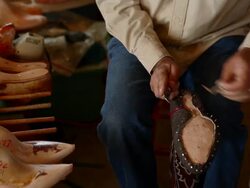 R/F TD PAN MS boot maker trimming excess leather from sole of cowboy boot Stock Footage