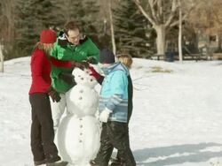 Family conrstucts a snowman Stock Footage