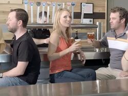 MS TS PAN bartender behind beer taps in micro brewery tasting room as young couples sit at bar toasting each other/ Thousand Palms, California, USA Stock Footage