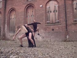 Slow motion two dancers leap simultaneously with industrial background, UK Stock Footage