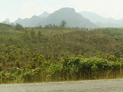 MS SLO MO Shot of farm tractor passing , green field and mountains/ Road from Luang Prabang to Nong Khio, Luang Prabang, Laos Stock Footage