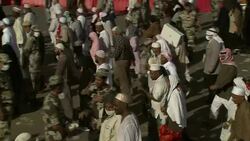 A migrating crowd passes armed military personnel as they head toward Mecca. Stock Footage