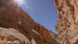 Tilt down from sunbeams to the canyon floor where a young hiker boy is admiring the scenery Stock Footage