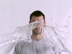 MS SLO MO Shot of Caucasian male against white canvas and water being thrown on him / Studio, New York, United States Stock Footage