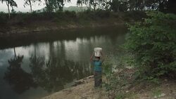 W/S-M/S Burmese teenage girl carrying water from a pond in a rural area Stock Footage